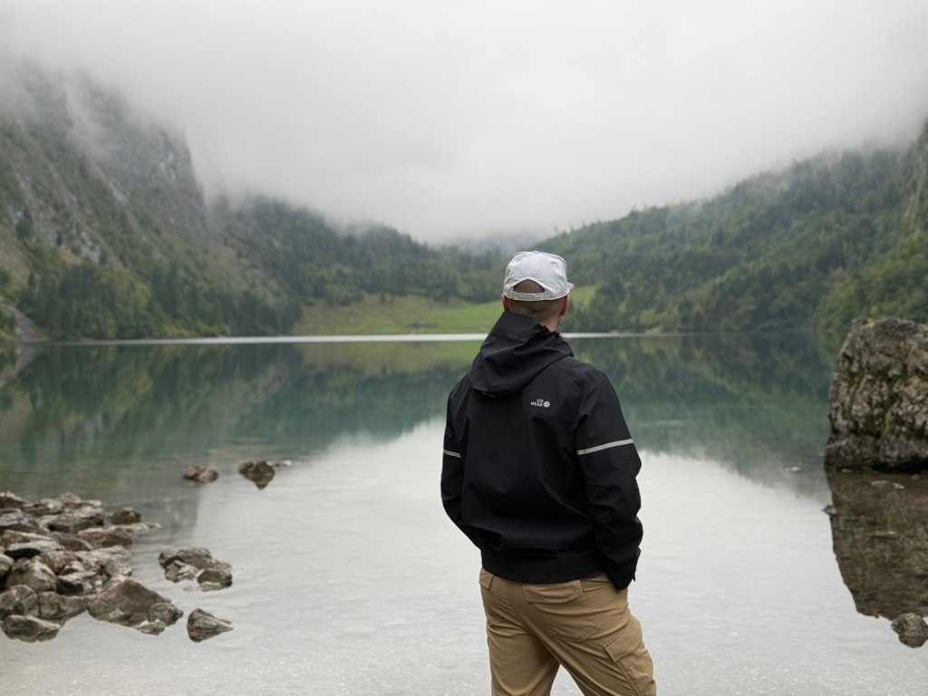 Julian standing by a misty lake in Germany with forested mountains in the background